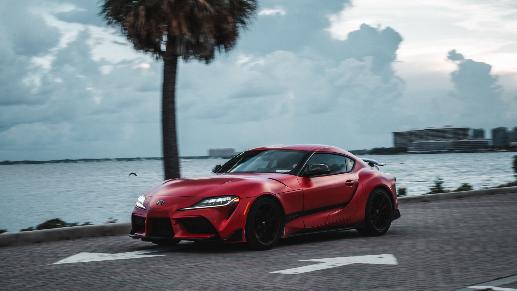Red Toyota Supra driving along the coast